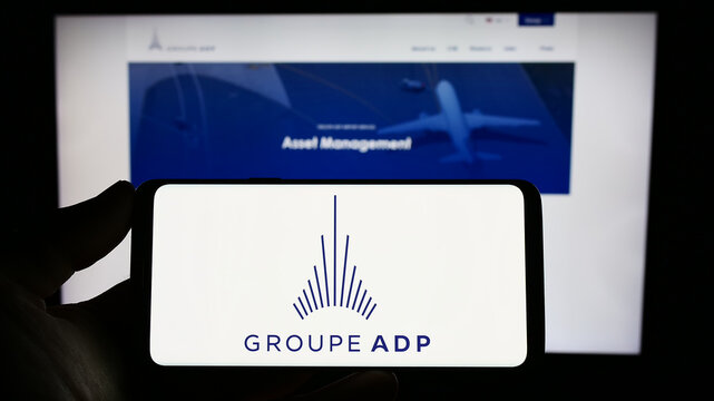 Stuttgart, Germany - 06-17-2023: Person holding smartphone with logo of French airport operator company Groupe ADP on screen in front of website. Focus on phone display.