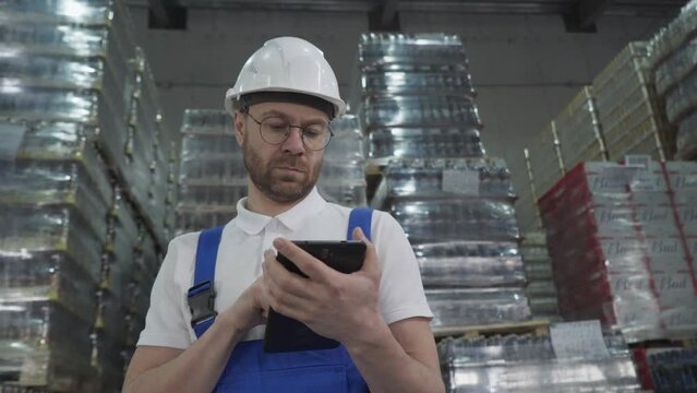 Storehouse manager inspects huge amounts of cargo collected at the plant. Storehouse manager uses a calculator to count the cargo. Storehouse manager estimating the amount of cargo supply.