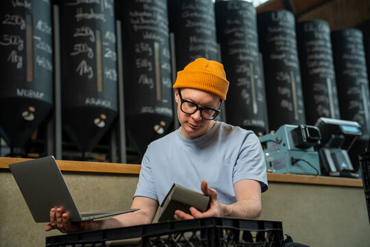 Barista working in coffee shop, accepts new product, checks the amount of coffee, using notebook