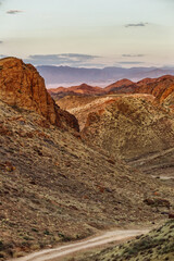 vertical photo gravel dangerous road in canyon mountains at red sunset