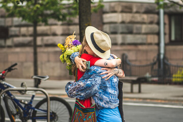 Young girls with tattoos and flowers meeting in the street and hugging for greetings, friendship and love concept