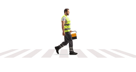 Road assistance mechanic walking at a pedestrian crosswalk and carrying a tool box