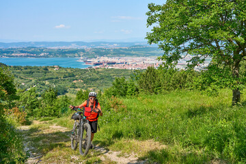Fototapeta na wymiar nice active senior woman on a mountain bike tour at the Slovenian Mediterranen cost above Koper at Capodistria