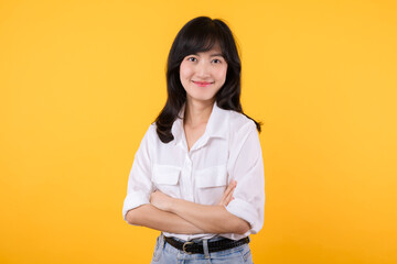 Young Businesswoman. Portrait asian woman happy smiling, posing confident, cross arms on chest, standing against yellow studio background. Smart young entrepreneur advertising products and services.