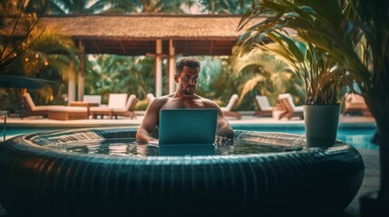man with computer in the pool of a hotel on vacation
