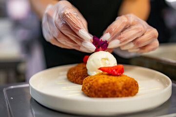 chef hand decorated cheese pancakes with ice cream and sweet sauce
