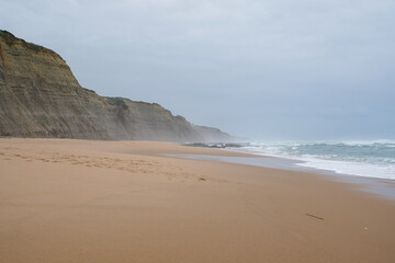 Praia do Magoito, Sintra, Portugal - March 2023: View of the ocean, rocks, sand and waves on the beach. Atlantic Ocean.