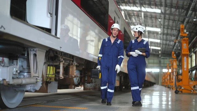 Railway Transportation Inspector With Engineer Checking and Maintaining part of train in station.