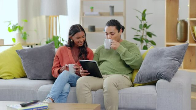 Tablet, sofa and happy couple with coffee, relax and talking, conversation or planning life together at home. Living room, tea or drink of interracial woman and partner on couch and digital streaming