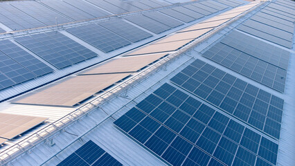 Fototapeta na wymiar Future green energy and sustainable electricity resource concept. Outdoor focus on solar panels on rooftops or photovoltaics of factories by drone. Industrial roof with solar cell grid with blue tone.