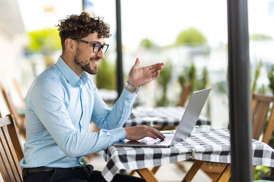 Businessman making video call by laptop in the cafe outdoors. - Powered by Adobe