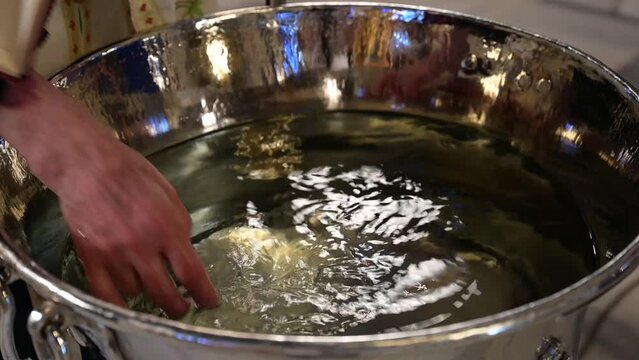 Priest blesses water for baby baptism