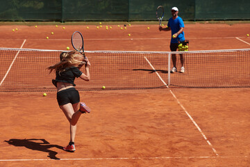 A professional tennis player and her coach training on a sunny day at the tennis court. Training...