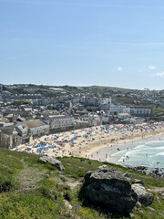 St Ives, Cornwall, UK - 29.05.2023. Crowds of holiday makers, day travellers and tourists enjoying the summer sunny day on the popular beach in St. Ives, England, UK. Holidays by the Atlantic Ocean.