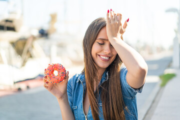 Young woman holding a donut at outdoors has realized something and intending the solution