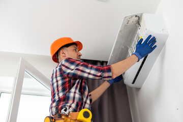 Professional technician maintaining modern air conditioner indoors