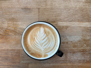 A cup of coffee latte on a wooden table. A mug of flat white coffee, latte, cappuccino on a wooden background. Coffee art. Heart flower swan shape latte art