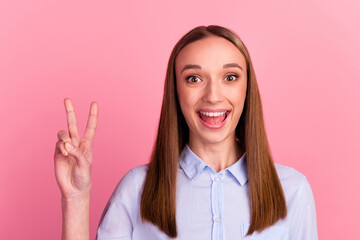 Young girl against pink wall makes peace gesture shows v sign body language concept