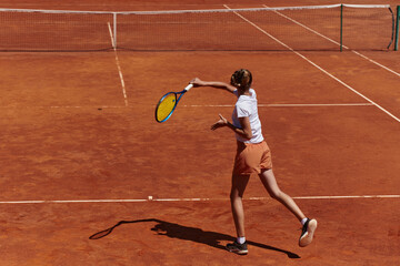 A young girl showing professional tennis skills in a competitive match on a sunny day, surrounded by the modern aesthetics of a tennis court.