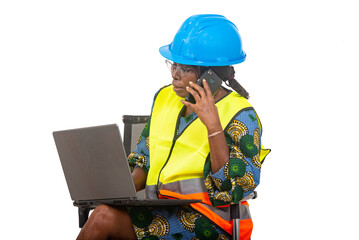 close up of smiling woman engineer in protective helmet working using laptop computer and mobile phone.