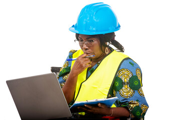 close up of female engineer in protective helmet working using laptop and clipboard, pensive.