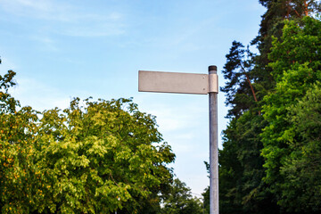 road sign with an empty place for destination name against the background of trees and sky