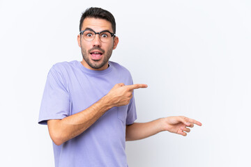 Young caucasian man isolated on white background surprised and pointing side