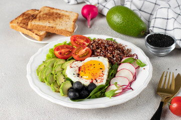 Healthy romantic breakfast - heart-shaped fried eggs served with avocado, spinach, quinoa, cherry tomatoes, radish and olives