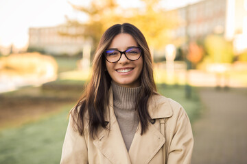 Cheerful LGBT female student wearing glasses joyfully smiling beautifully in front of campus - obrazy, fototapety, plakaty