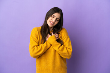 Young caucasian woman isolated on purple background having a pain in the heart