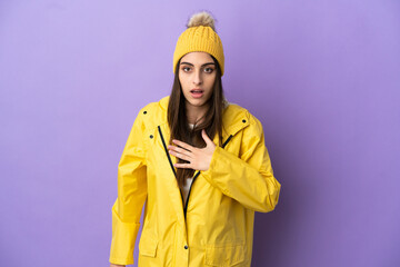 Young caucasian woman wearing a rainproof coat isolated on purple background surprised and shocked while looking right