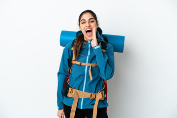 Young mountaineer man with a big backpack over isolated background shouting with mouth wide open