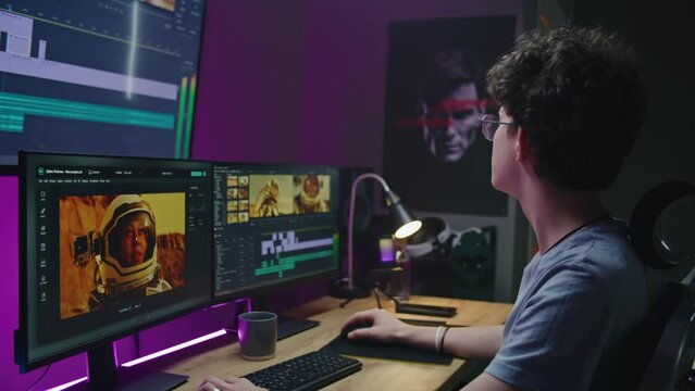 Young video maker edits movie about space mission, works at home office. Film footage and program interface with tools and sound tracks on computer and big digital screen. Concept of post production.