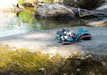 River stream rapids in beautiful summer in Ukraine. Children's shoes, sandals on a large stone near the water