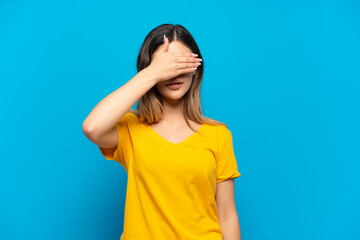 Young Russian girl isolated on blue background covering eyes by hands. Do not want to see something