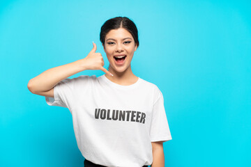 Young Russian volunteer girl isolated on blue background making phone gesture. Call me back sign