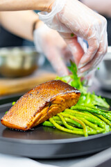 woman chef hand cooking salmon steak with asparagus and salad