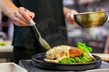 woman chef hand cooking salmon steak with asparagus and salad
