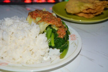 A plate of pecel rice, on a white background.