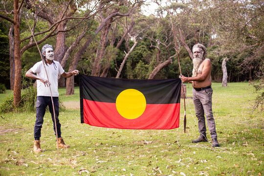 Two dharawal men holding the Australian aboriginal flag