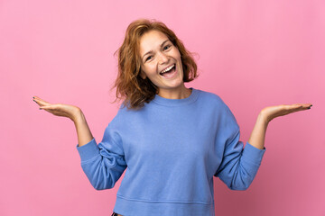 Young Georgian woman isolated on pink background with shocked facial expression