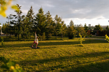 Wide shot of unrecognizable flexible young woman stretching body muscles on nature. Yogini female...