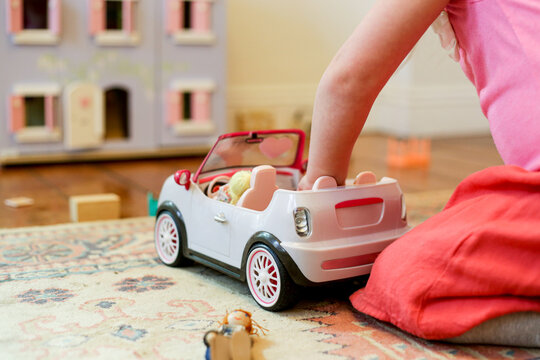 Young girl playing with a toy car with dollhouse
