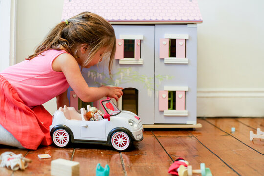 Young girl playing with a dollhouse and toy car