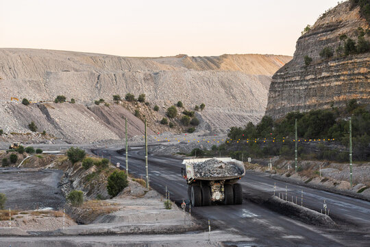 Heavy mine machinery driving away in open cut coal mine moving rocks and earth
