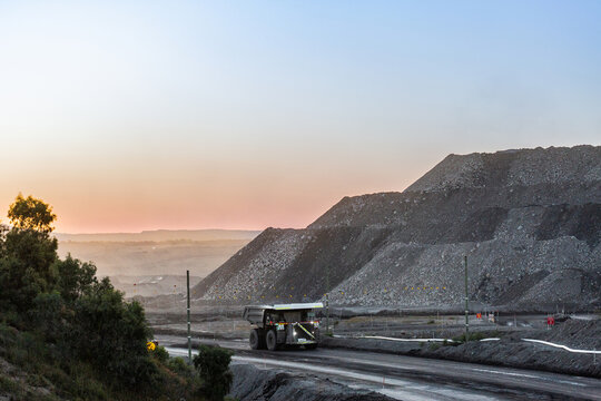 Big machinery working in open cut coal mine at the end of the day with dusk light behind slag hills