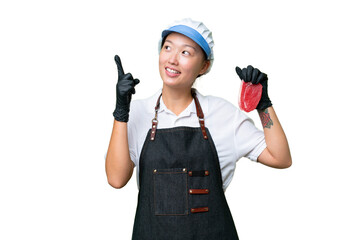 Young caucasian woman wearing an apron and serving fresh cut meat over isolated background pointing up a great idea