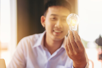 Businessman sharing an idea concept, Man holding a light bulb of idea and sharing to his colleague. Selected focus