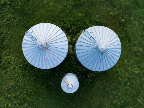 Overhead aerial view of three grain storage silos on a farm