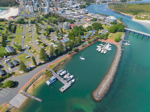 Aerial view of a sheltered marina on a coastal river alongside a city caravan park